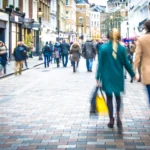 Motion blurred shopping couple walking on busy high street scene